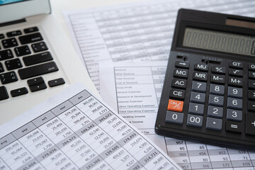 Accounting business concept. Calculator with accounting report and financial statement with laptop computer on desk.