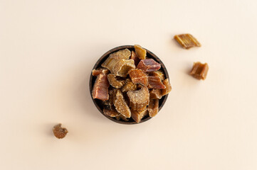 Candied rhubarb. Pieces of Jerky rhubarb in a wooden plate on a beige background. Selective focus. Healthy sweets.