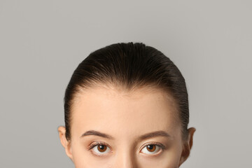 Young woman with beautiful eyebrows on grey background