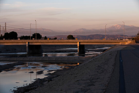 Sunset View Of The Santa Ana River As It Winds Its Way Through Anaheim With Snow Capped Mountains In The Distance.