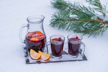 Glass with mulled red wine on a bed of snow and white background, close up. Christmas beverage