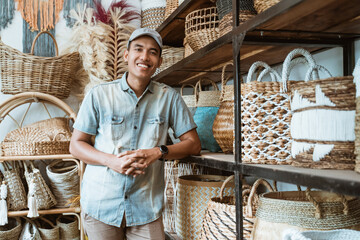handicraft business owner with his hands leaning back on a shelf while in a handicraft shop with...