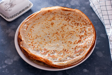 Cooked thin pancakes on milk on a white plate, horizontal
