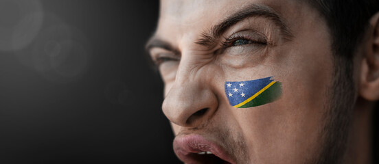 A screaming man with the image of the Solomon Islands national flag on his face