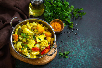 Sabji, Stewed pumpkin with soft cheese and vegetables on a dark stone table. Traditional Indian food. Copy space.
