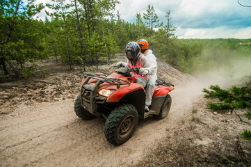 Unrecognizable people driving a quad bike on the dangourous roads of