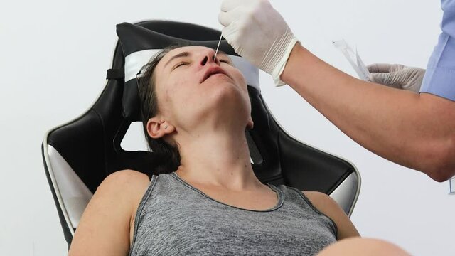 Young female tacking a CPR covid test. Home coronavirus quick Rapid Diagnostic Test RDT. Medical worker collects nasal swab from patient nose in the comfort of own house