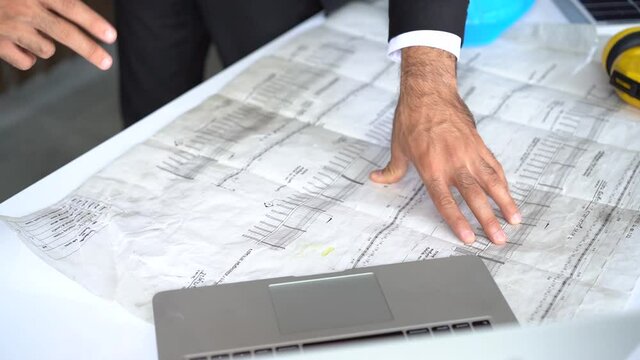 Businessman and Engineer Hand Drawing Plan On Blue Print with architect equipment discussing the floor plans over blueprint architectural plans on the table.
