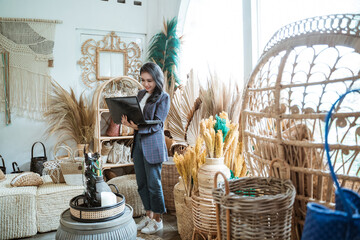 woman entrepreneur using a laptop while standing among exotic handicrafts in a craft shop