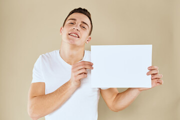man in white t-shirt sheet of paper in hands Copy Space cropped view beige background