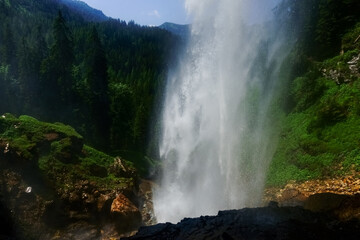 huge waterfall from a high cliff with view to the forest