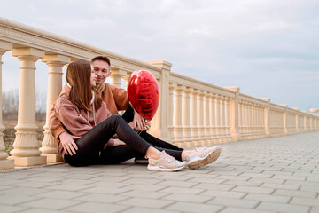 Young loving couple embracing each other outdoors in the park holding balloons