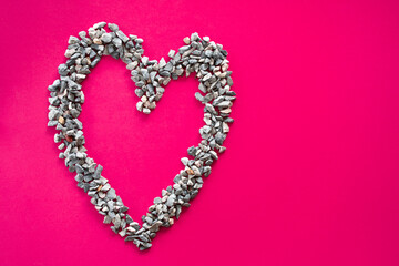 Heart symbol Made of small stones Or pebbles placed on a pink background. It is a concept of love day or Valentine's day. Take a top view and close-up
