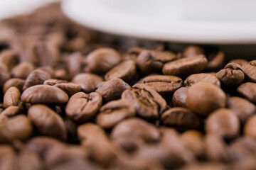 roasted coffee beans near a saucer from a cup of coffee