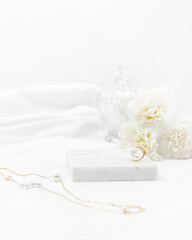Obraz na płótnie Canvas White women cosmetic desk decorated with marble white fabric golden ring necklace and flower