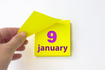 January 9th. Day 9 of month, Calendar date. Hand rips off the yellow sheet of the calendar. Winter...
