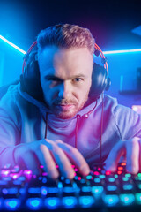 Streamer professional cyber sport gamer playing online computer game with headphones, Blurred Red and Blue background © Parilov
