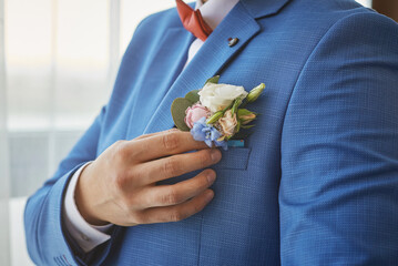 bride adjusts the boutonniere on his suit. preparing for the wedding.