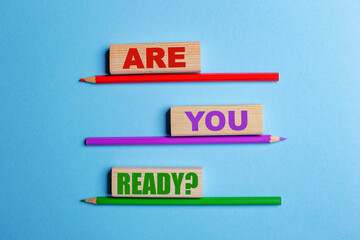 On a blue background, three colored pencils, three wooden blocks with text QUESTION ARE YOU READY