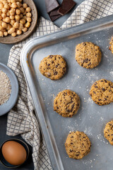 Vertical composition of a baking tray with freshly baked chickpea cookies and dark chocolate chips