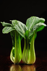 Bok choy fresh standing on table, black background