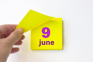 June 9th. Day 9 of month, Calendar date. Hand rips off the yellow sheet of the calendar. Summer...