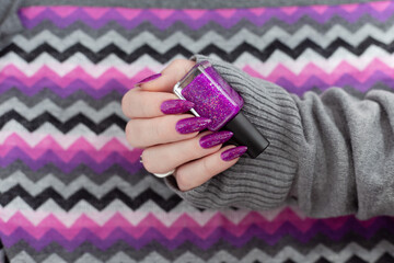Womans hands with long nails with violet purple nail polish