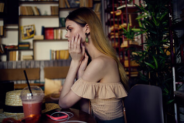 Pretty woman sits at a table in a restaurant having fun and relaxing glass with a drink