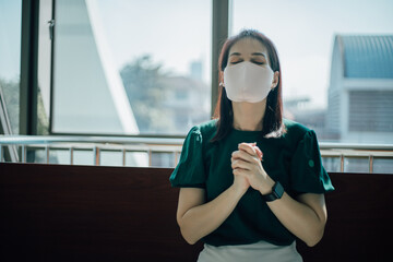 Woman stay at church wearing face mask for protect coronavirus covid-19. Prayer female worship god and praying for coronavirus crisis.