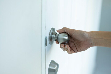 close up female hand holding a door knob or door handle in a house
