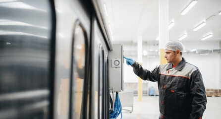 Factory engineer man operating machine control panel in dairy milk production plant