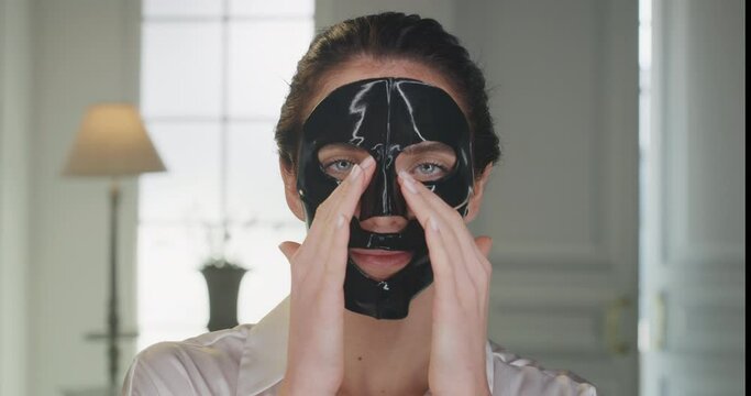 Beauty shot of young woman wearing deep cleaning blackhead remover mask ready for moisturizing anti wrinkle day or night cream is smiling in camera. Concept of skincare, cosmetics, healthcare, acne.