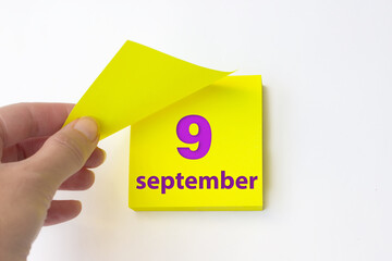 September 9th. Day 9 of month, Calendar date. Hand rips off the yellow sheet of the calendar....