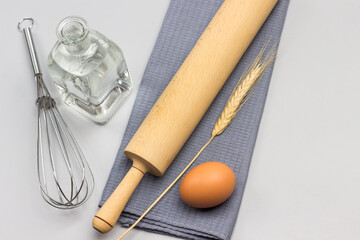 Rolling pin, egg and spikelet of wheat on gray napkin