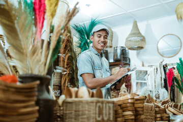 smiling man holds the clipboard while list items among craft items in the craft gallery