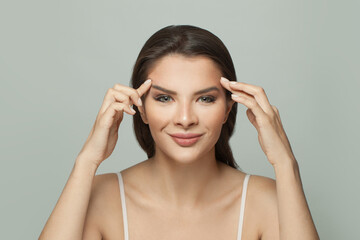 Fototapeta premium Smiling woman holding her hands near her face. Massage, face gymnastics, cosmetology and aesthetic medicine concept