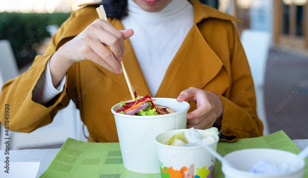 Wall mural woman having noodles meal in the restaurant from the paper box