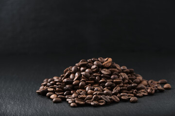 A pile of coffee beans on a textured black stone