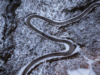 Road with curves and hairpin bends in a snowy forest