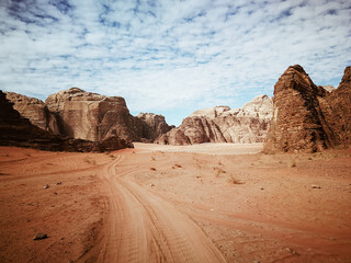 empty road in the wadi rum desert, beautiful relief mountains are on the horizon, beautiful cloudy sky, panoramic view, nature of jordan