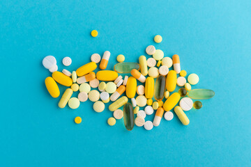 Assorted pharmaceutical medicine pills, tablets and capsules over blue background, with copy space. Flat lay, top view. Close up.