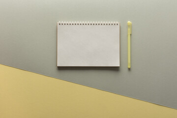 Open spiral notepad on gray and yellow background , notebook and pen lie on textural paper, flat lay concept in trendy colors of the year yellow and gray