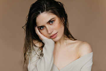 Glad dark-haired girl looking to camera. Studio shot of glamorous pensive woman.