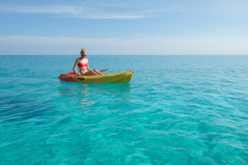 girl paddles a kayak in the turquoise waters, vacation in Cuba