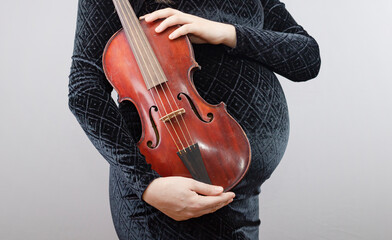 Pregnant woman with red violin isolated on gray background.