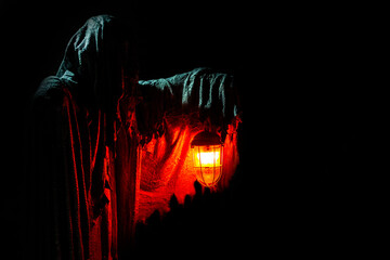 
The ghost holds a burning lantern on a dark background. Horror.