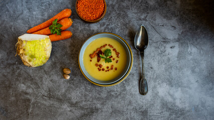 A Bow of Celery Soup with celery stalk, celery, carrot,lentil,nutmeg on grey background