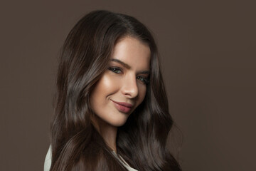 Obraz na płótnie Canvas Beautiful young woman face with healthy clear skin and long hair on brown background