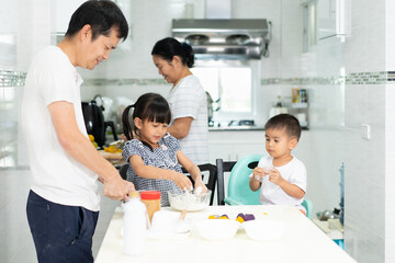 Multigeneration people in the family are happy to prepare and cooking the dessert in the kitchen with happy moment, concept of practical life learning for child through home based activity.