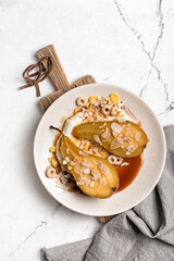 Tasty dessert of baked pears with caramel sauce, cheese cream and almond flakes